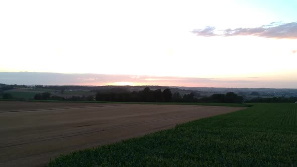 Rise above crop fields and valley at sunset, drone shot