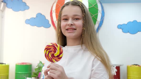 Close Up Portrait of Beautiful Cute Baby in White Tshirt Holding Lollipop and Looking at Camera