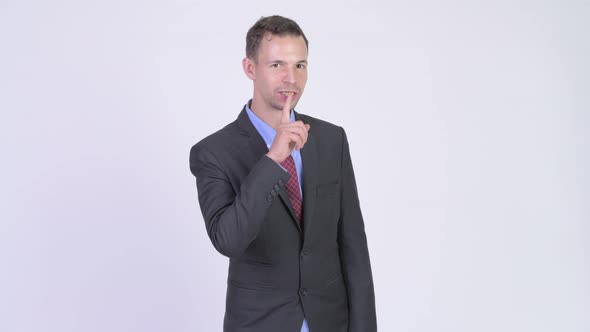 Studio Shot of Happy Businessman with Finger on Lips