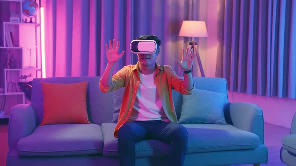 Asian Man Wearing Vr Headset At Living Room And Using Finger Touching , Cyan And Magenta Colors
