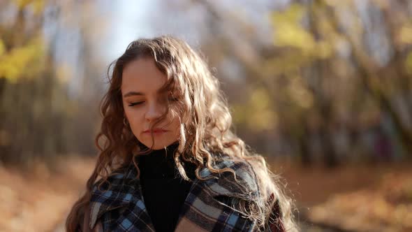 Autumn Melancholy Charming Woman is Walking in Park in Sunny Day Wearing Warm Coat