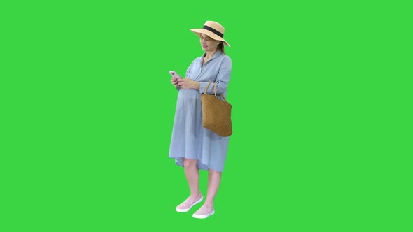 Pregnant Woman on the 9Th Month Using a Smartphone on a Green Screen, Chroma Key.