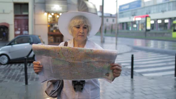 Senior Female Tourist Exploring Town with a Map in Hands. Looking for the Route