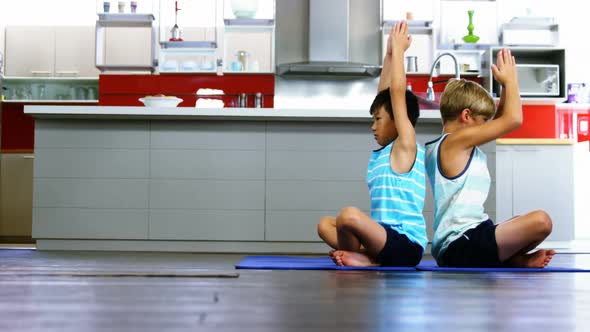 Siblings practicing yoga in kitchen