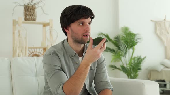 Man at Home Sitting on the Sofa Sending Voice Message on the Phone