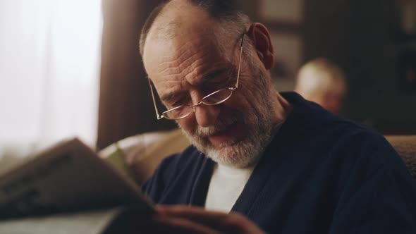 Grandfather Reading a Newspaper on Sofa