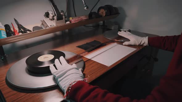 A man with white gloves working at a film studio examines a film strip