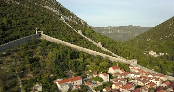 Aerial shot of Ston in Croatia, an ancient walled city, the camera follows the walls over the hills