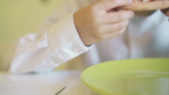 Happy Boy Eats Pizza Above Green Plate at Table Close View