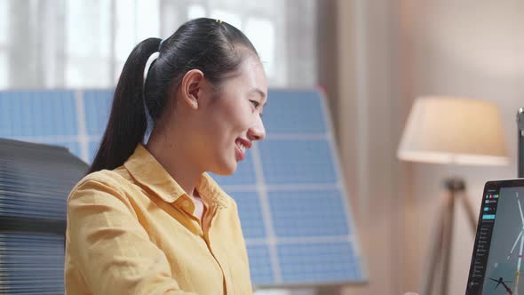 Close Up Of Asian Woman Looking At A Laptop Showing Wind Turbine On The Table