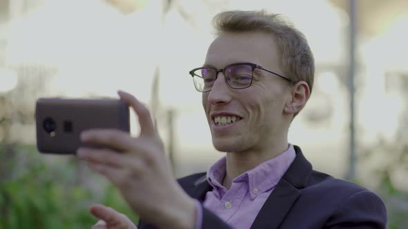 Smiling Young Man in Eyeglasses Having Video Call Through Phone