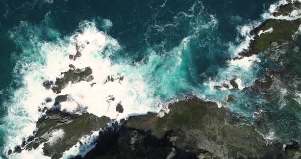 Static overhead shot of sea waves of Indian Ocean hitting boulder and rocks in the beach in sunny co