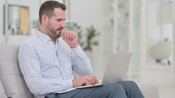 Sick Young Man Using Laptop Coughing at Home
