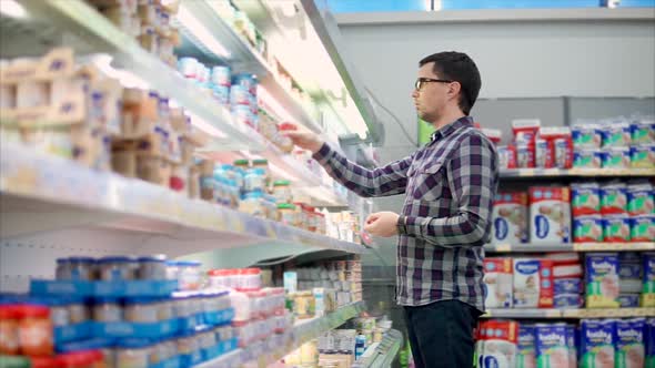 Adult Man Chooses Baby Food on the Shelves in the Hypermarket