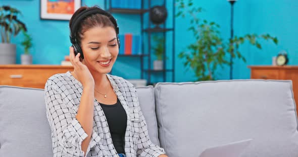 Young Women Sitting on Sofa with Laptop Crossed Legs She Has Wireless Headphones on Ears alt