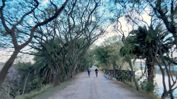 A Beautiful Dolly Shot Following Cyclists Along a Road in the Costanera Sur Ecological Reserve in Pu