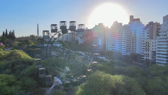 Drone flyover rustic ferries wheel reveals stairway lookout platform with sun glowing in the backgro