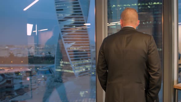 Full Length Back View of Successful Businessman in Suit Walking in Office with Hands in Pockets