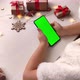 Cute girl in Santa hat holding smartphone with vertical green screen. - VideoHive Item for Sale