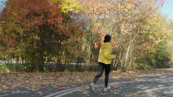 Girl Running on Track at the City Park in Sunny Autumn Morning Back View