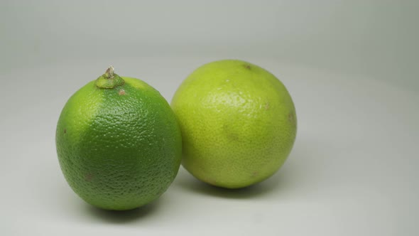 Two Ripe Green Citrus Fruits Lime Rotating Clockwise On The Turntable With White Background - Close