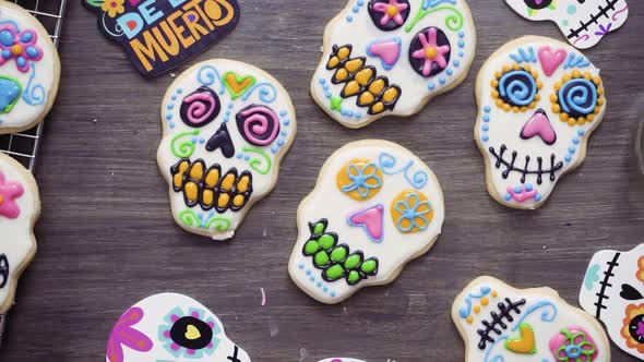 Step by step. Flat lay. Decorating sugar skull cookies with different color royal icing.