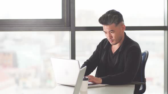 Portrait of Asian Male Lawyer at His Desk in the Office Looking at His Personal Computer