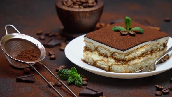 Portion of Traditional Italian Tiramisu dessert and pieces of chocolate bar