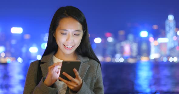 Business woman using cellphone in Hong Kong city at night