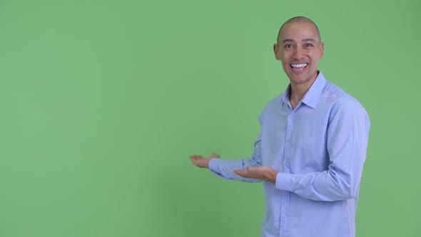 Happy Bald Multi Ethnic Businessman Showing To Back and Looking Surprised