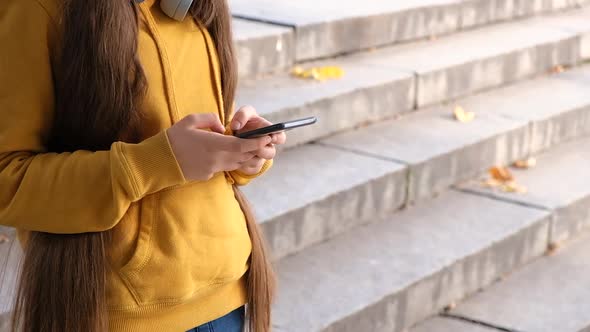 A Teenage Girl Uses a Smartphone Types Text on Her Phone and Drives Her Fingers Across the Screen