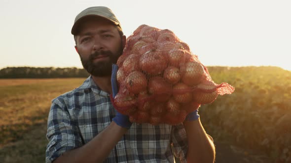A Smiling Farmer Carries a Bag of Onions on His Shoulder