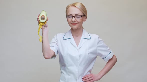 Nutritionist Doctor Healthy Lifestyle Concept - Holding Organic Avocado Fruit and Measuring Tape