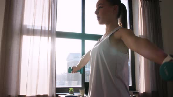 Teenage Girl with Dumbbells Exercising at Home