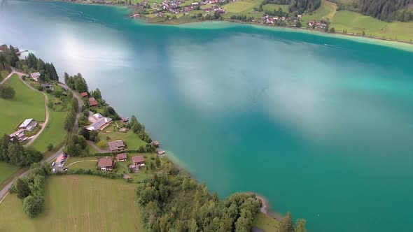 Drone flight over turquoise lake Weissensee in Austrian province of Carinthia