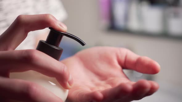 young man squeezes a white liquid disinfectant gel on his hand