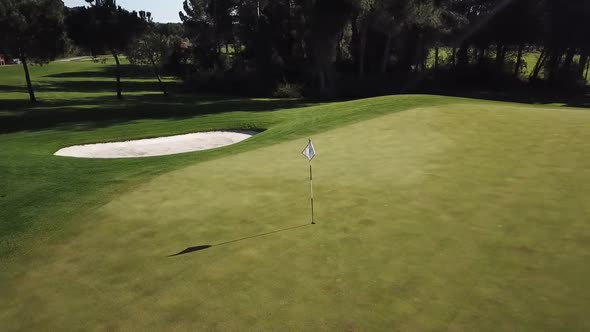 Flying around flag pole in vivid and vibrant golf field on sunny day