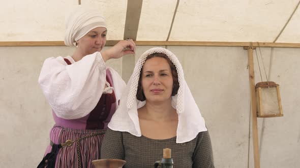 Three medieval woman sewing. They dressed in medieval clothes.