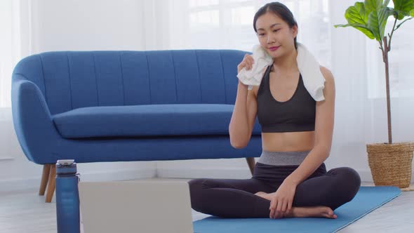Athlete Asian young woman resting after yoga exercise with friends in online class at home