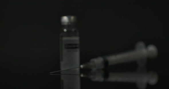 Coronavirus Vaccine And Syringe In The Dark