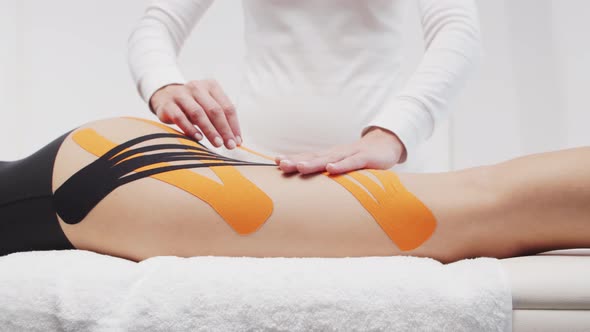 Therapist is applying kinesio tape to female body. Physiotherapy, kinesiology and recovery.