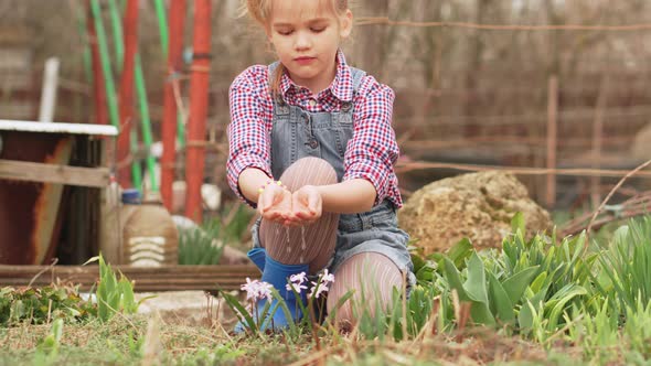 a Little Girl Watering Flowers From the Palms of Her Hands