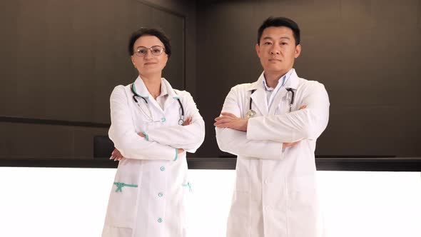 Confident Multinational Doctors in Lab Coats Posing on Camera with Crossed Arms