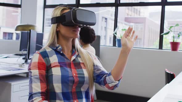 Caucasian businesswoman sitting and using vr googles in modern office