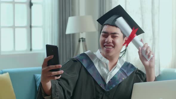Excited Man Showing A University Certificate During An Online Video Call By Mobile Phone At Home