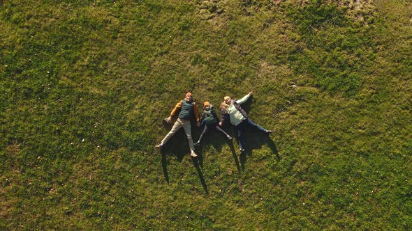 A Family of Three Father Mother and Son are Lying on the Grass in a Park