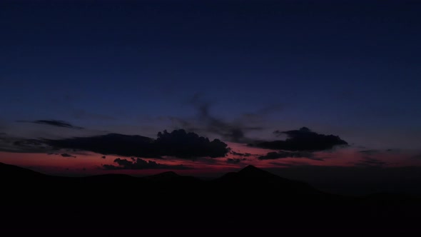 Silhouette of Mountains Under Sunset Sky with Clouds