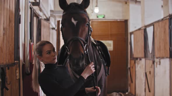 A Woman Putting on a Harness and Preparing the Horse for a Ride