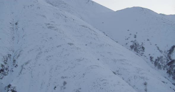 Closeup on Alaska State Trooper helicopter flying helicopter in front of mountains, drone aerial foo