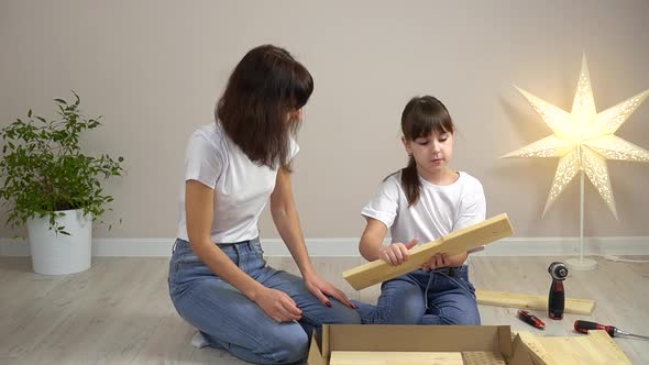 Happy Family Mother and Daughter Unpack New Wooden Furniture Together